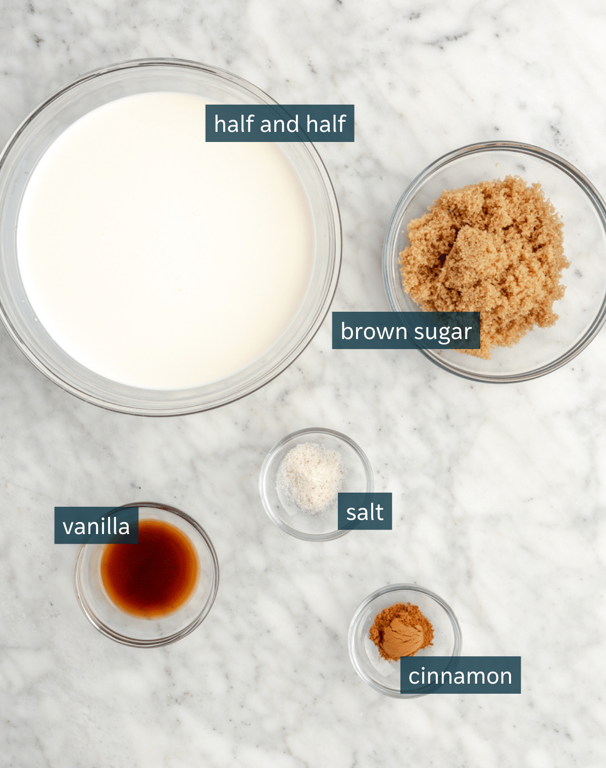 All of the ingredients needed for brown sugar creamer in separate small bowls on a marble surface.