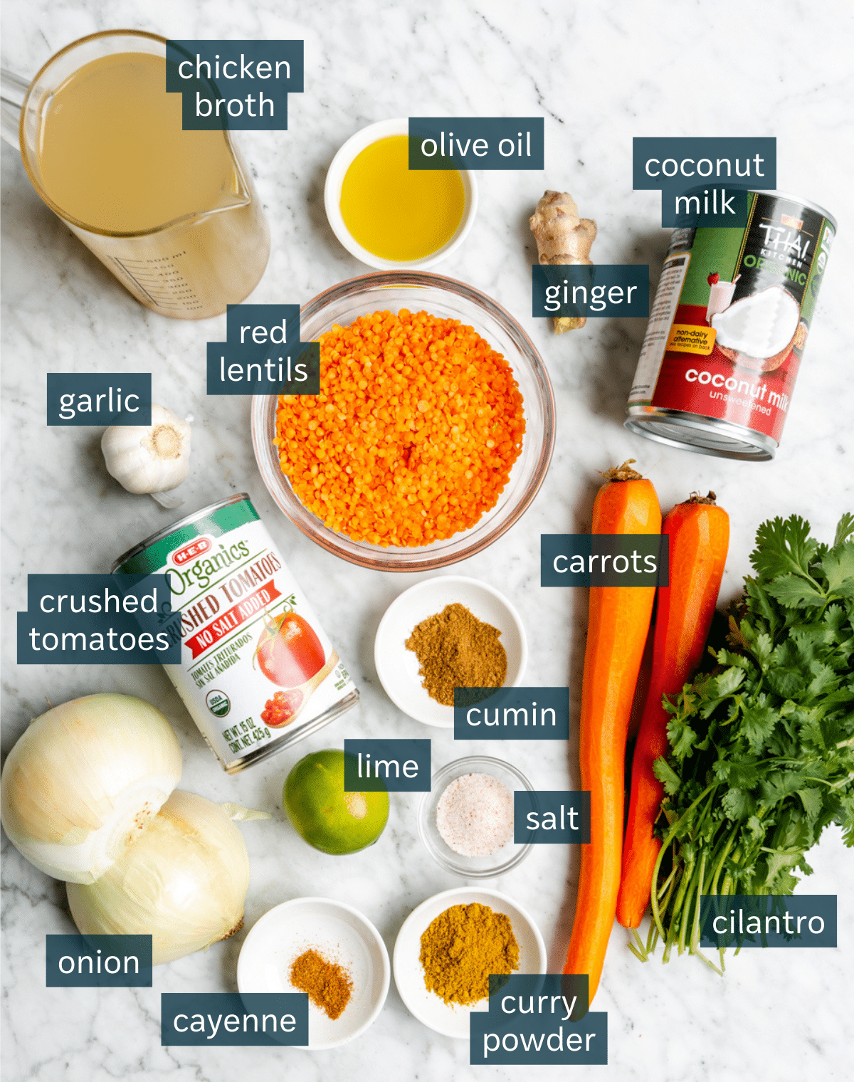 Top down view of lentil soup ingredients on a gray and white marble surface.