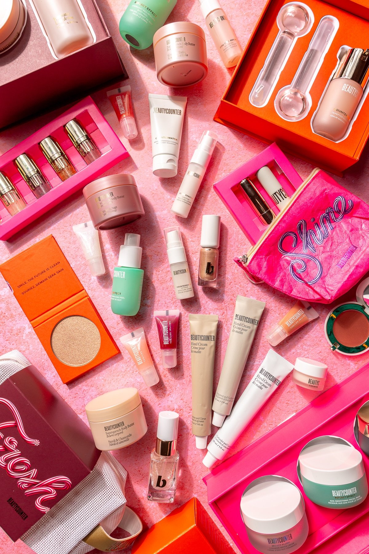An assortment of holiday gift sets from Beautycounter on a pink background.