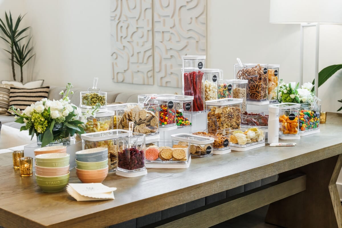 A bunch of Zwilling Fresh and Save containers filled with various snacks on a large wood table.