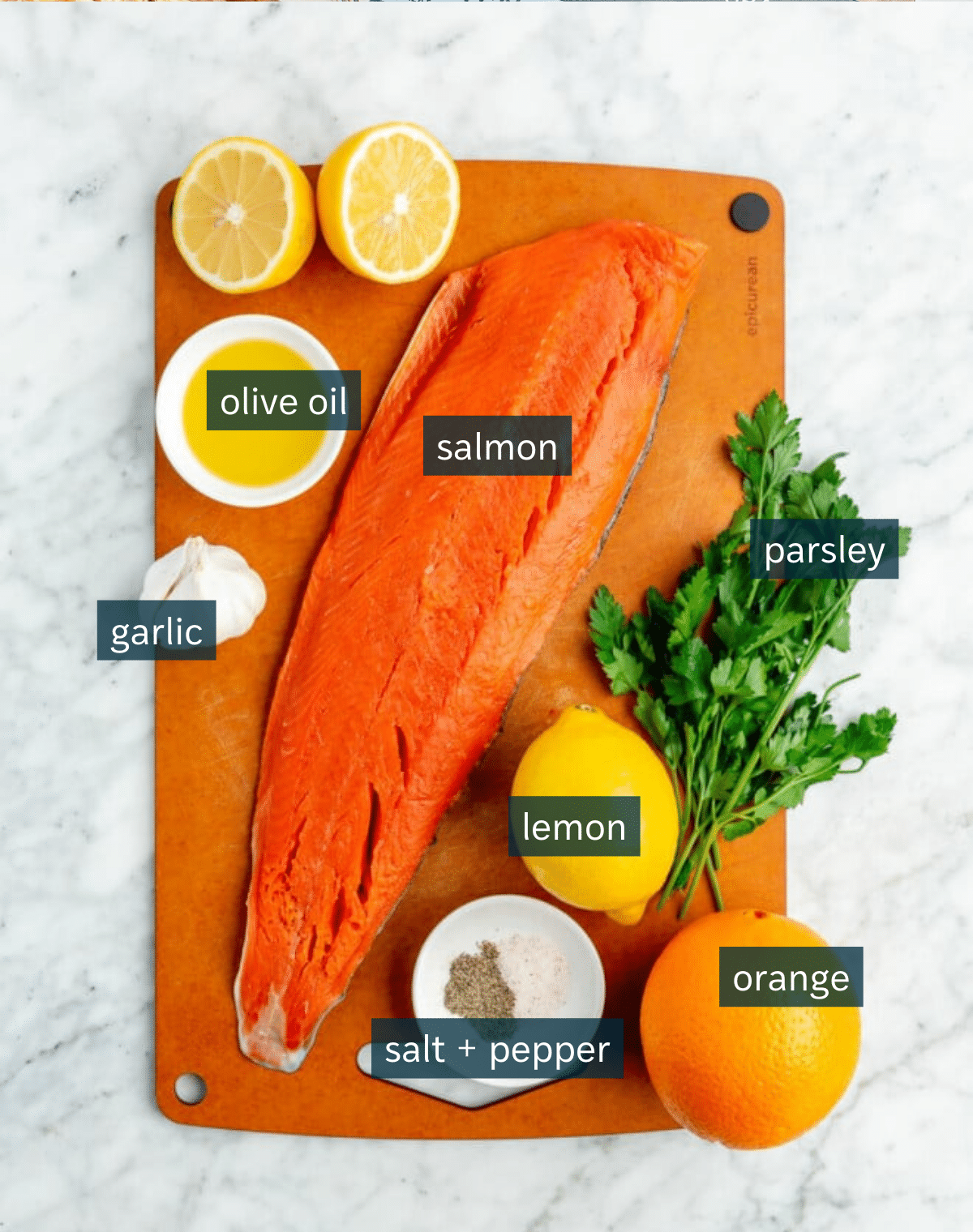Ingredients for easy citrus roasted salmon sit on an orange cutting board which sits on a marble countertop.
