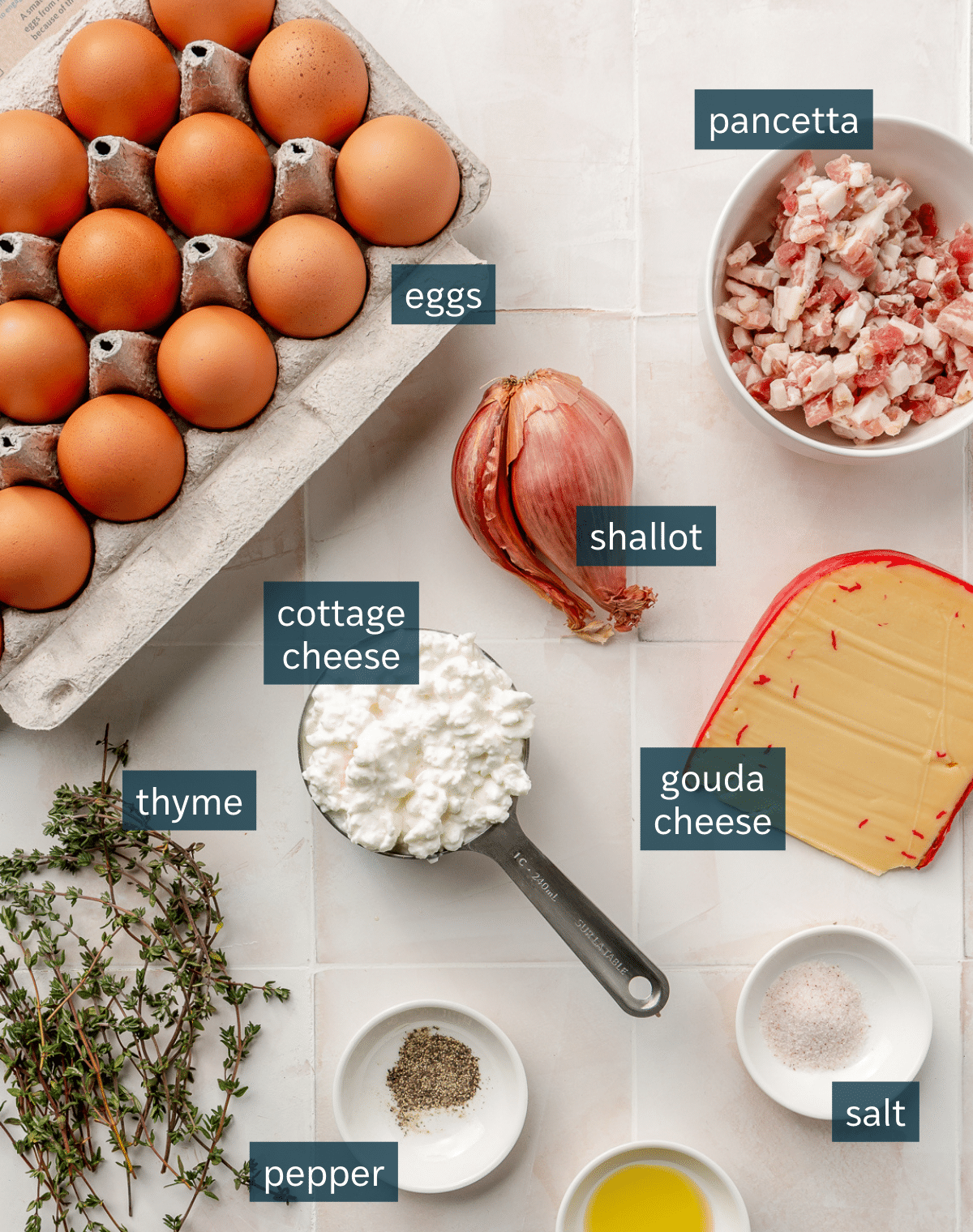 Ingredients for crustless quiche Lorraine sit in a variety of bowls on a white tiled countertop.