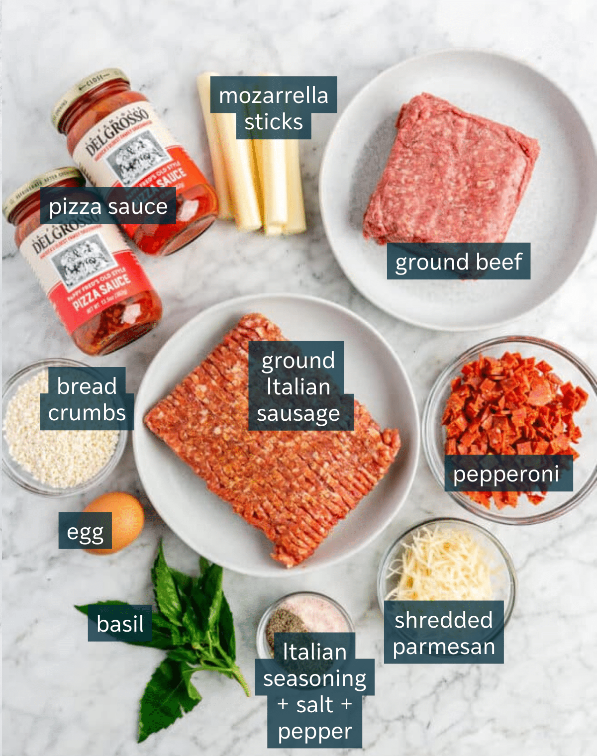 Ingredients for pepperoni meatballs sit in a variety of bowls on a marbled countertop.