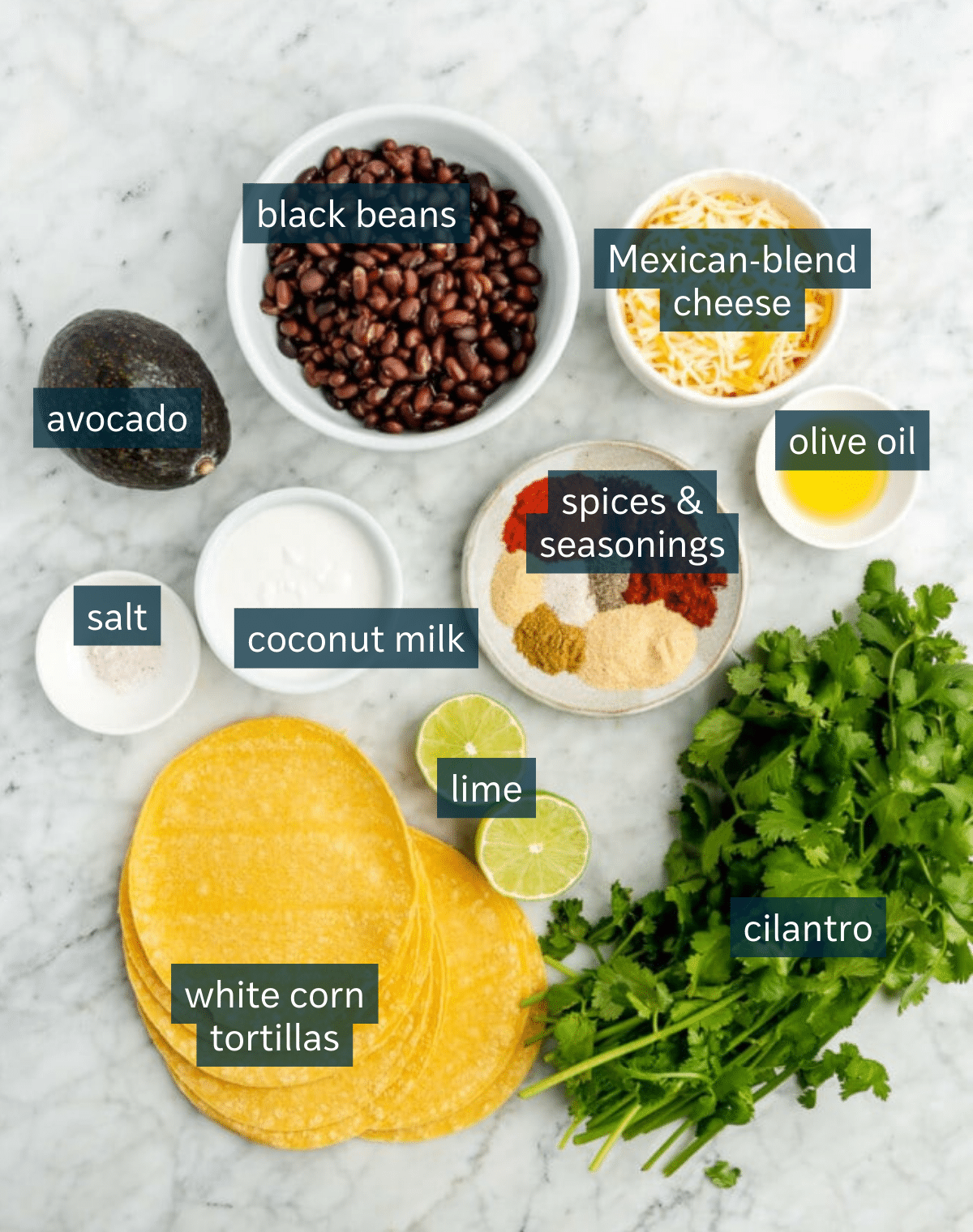 Ingredients for crispy black bean tacos sit in a variety of bowls on a marble countertop.