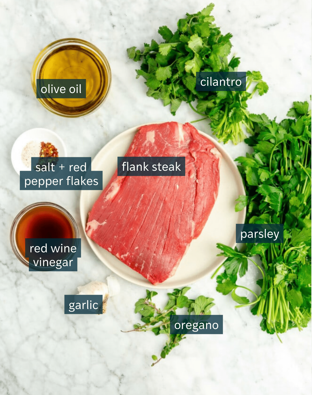 Ingredients for flank steak with chimichurri sauce sit on a marble countertop