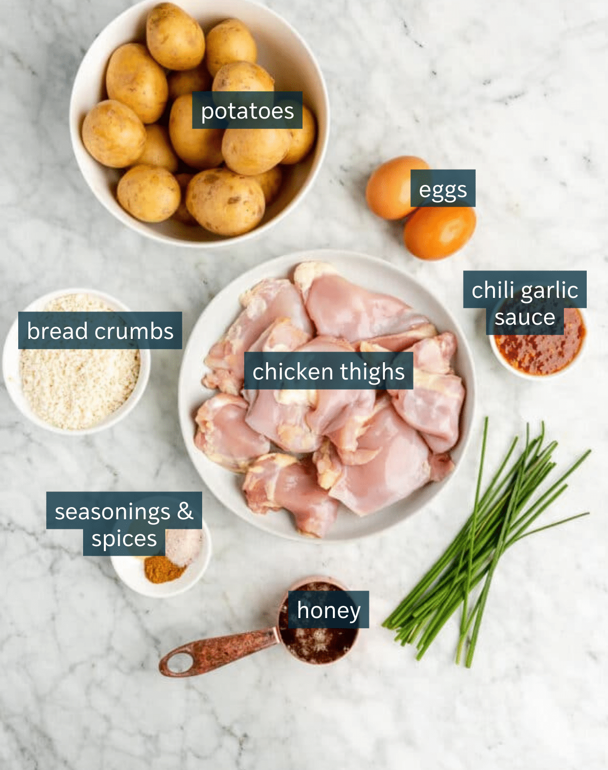 Ingredients for hot honey chicken sit in a variety of bowls on a marble countertop.