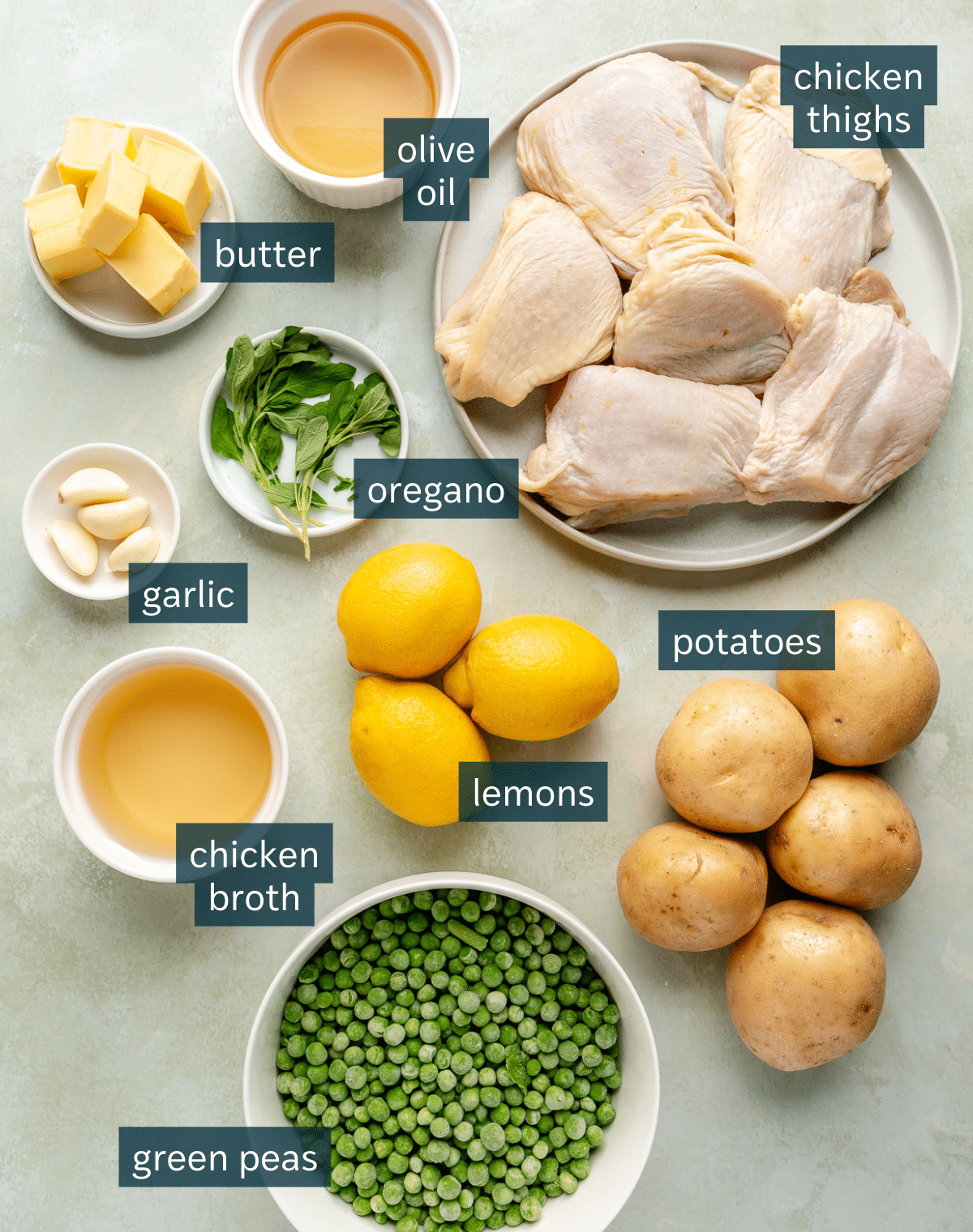 Ingredients for chicken vesuvio sit in a variety of bowls on a light green surface.