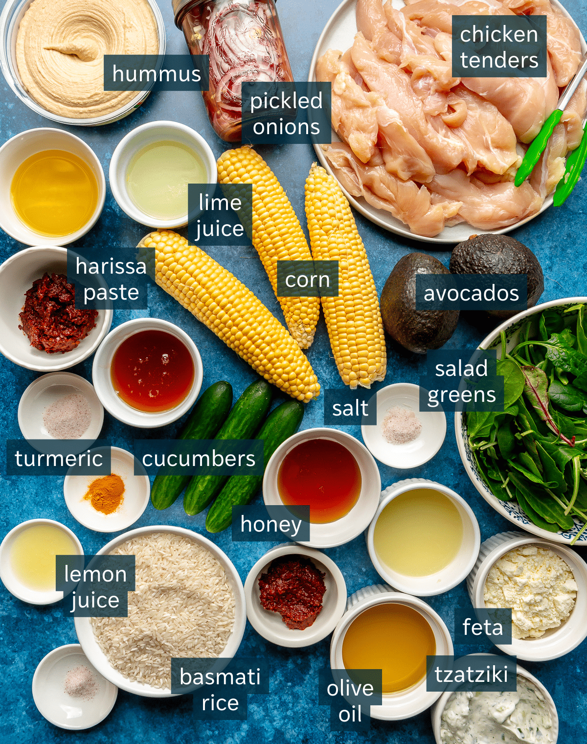 Ingredients for harissa honey chicken bowls sit on a dark blue countertop.