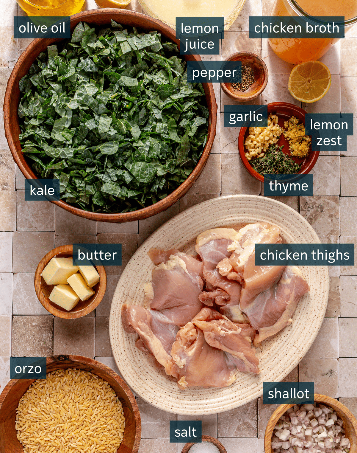 All of the ingredients for lemon chicken orzo soup in different sized bowls on a square tile surface.