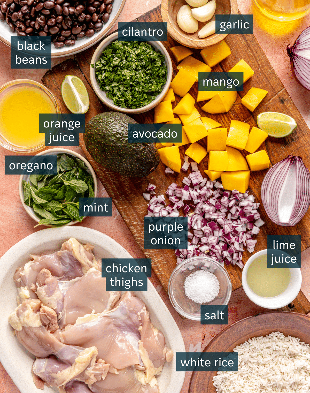 All of the ingredients for Mojo chicken bowls in small bowls on a pink surface.