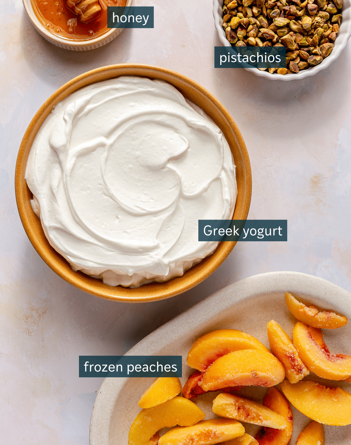 All of the ingredients needed for peaches and cream yogurt bark measured out in bowls on a light colored surface.
